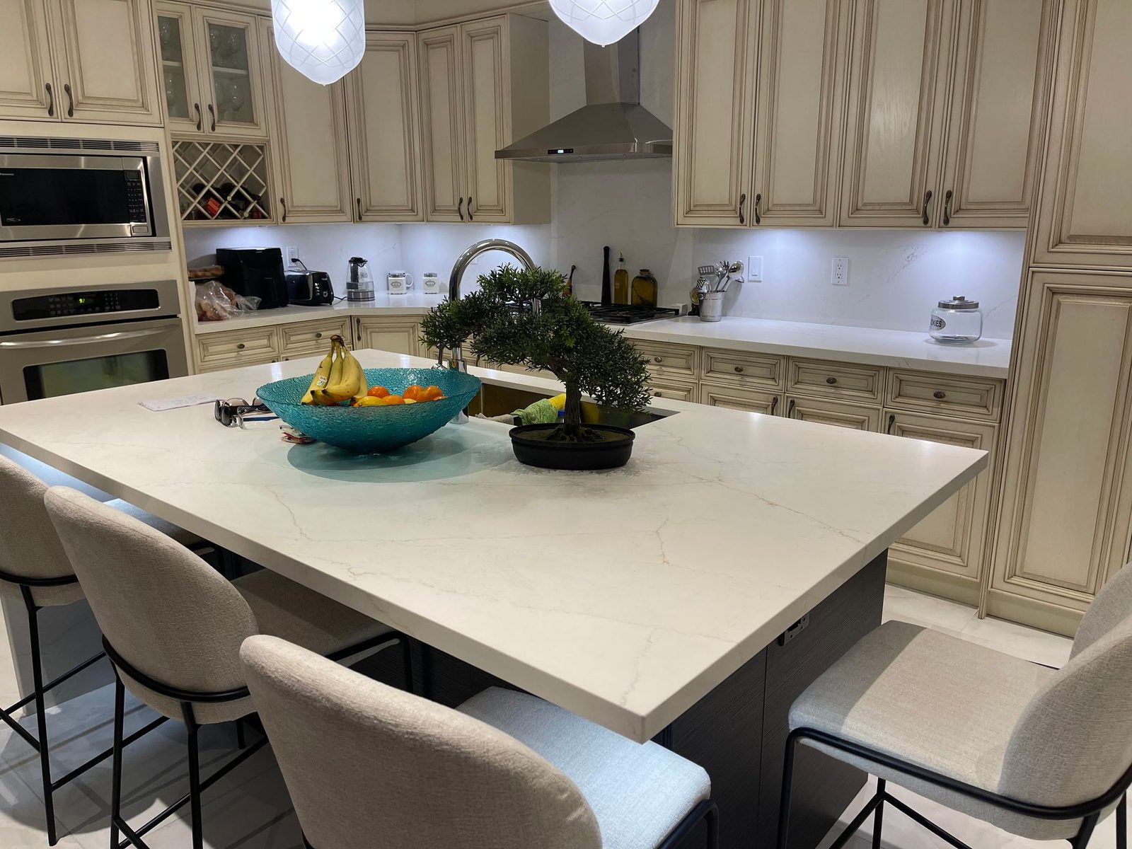 Custom kitchen with cream cabinetry, a large central island with stools and pendant lighting