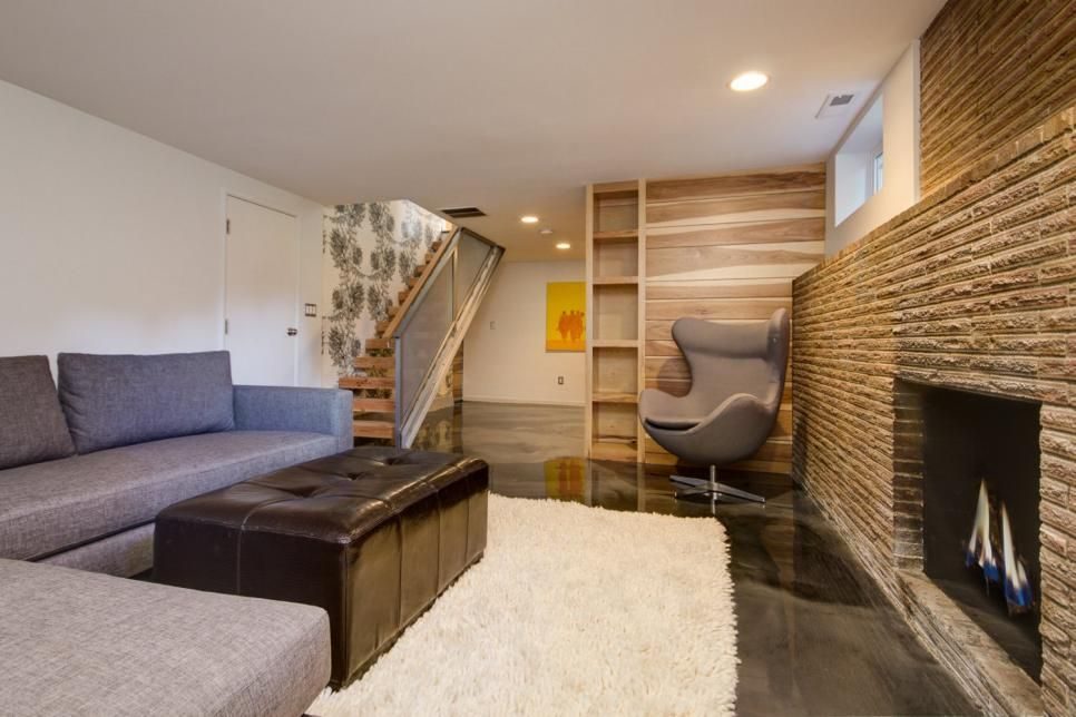 Basement living room with a floor-to-ceiling stone fireplace, wood accent wall and a modern egg chair